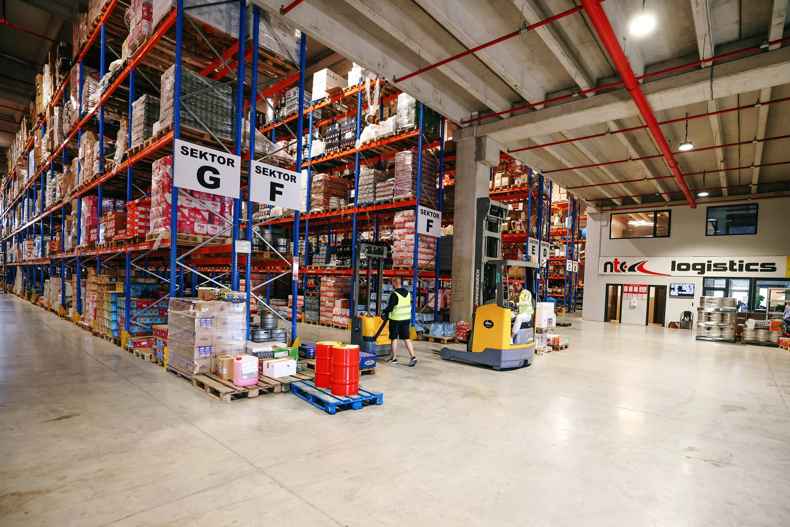 Warehouse hall with pallet racks and forklift operators